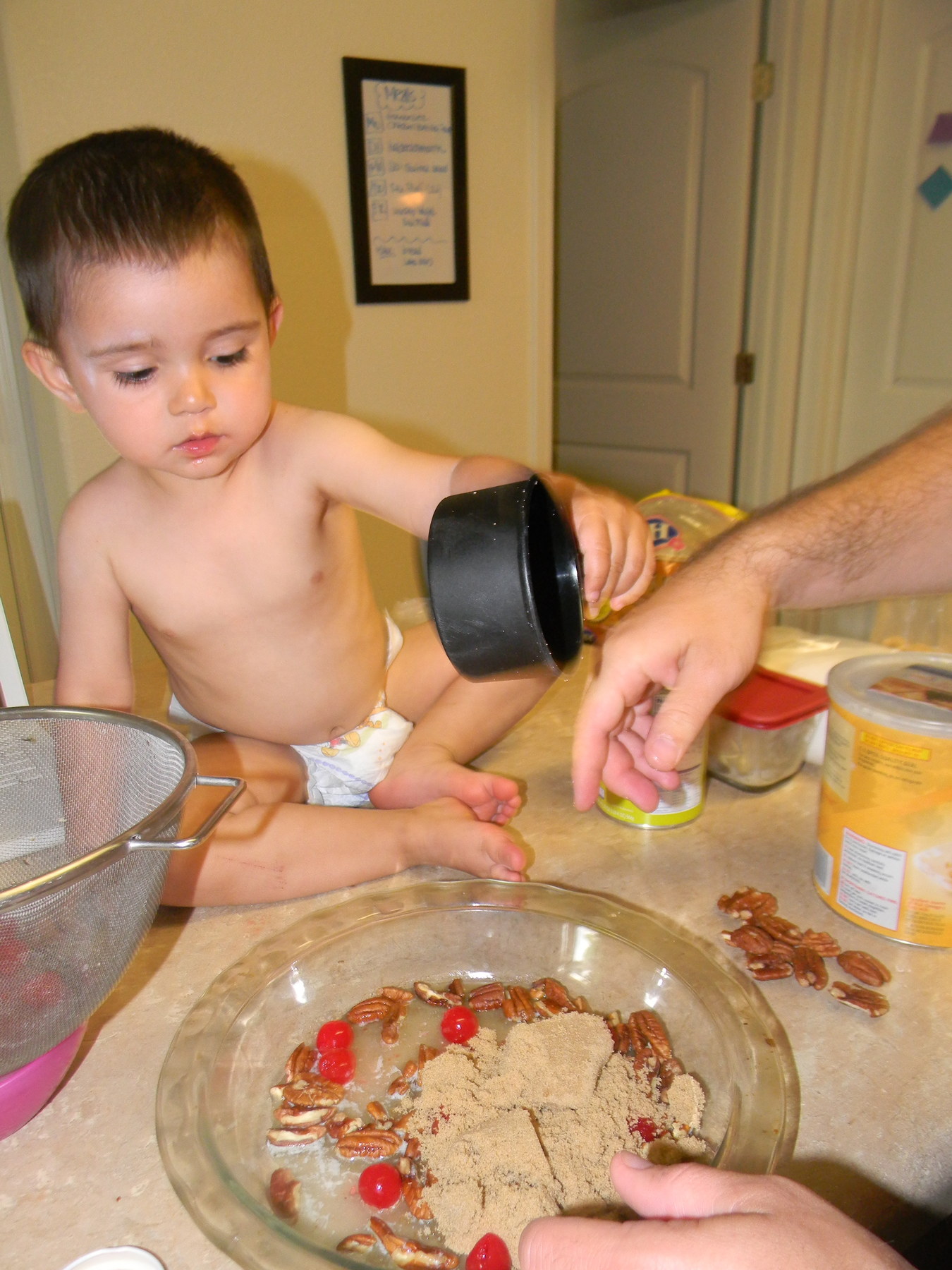 Judah helping John making pineapple upside-down cake (his biggest contributions were eating the cherries and trying to dump a whole bag of peanuts in the batter)
