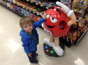Titus next to a statue of a red M-and-M character, about the same size as he is.