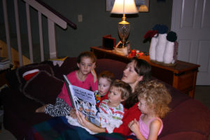 Titus sits on his Auntie Maria's lap while she reads a book to him, Elayne, and two of their cousins.