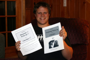 Jordan holding up printouts of his two Cherokee linguistic write-ups.
