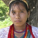 Mexican girl with red and orange beads over a green and blue shirt
