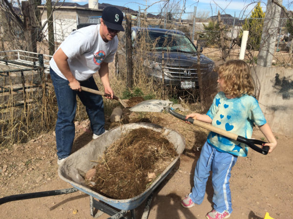 Jordan and Elayne shoveling dirt into a wheelbarrow