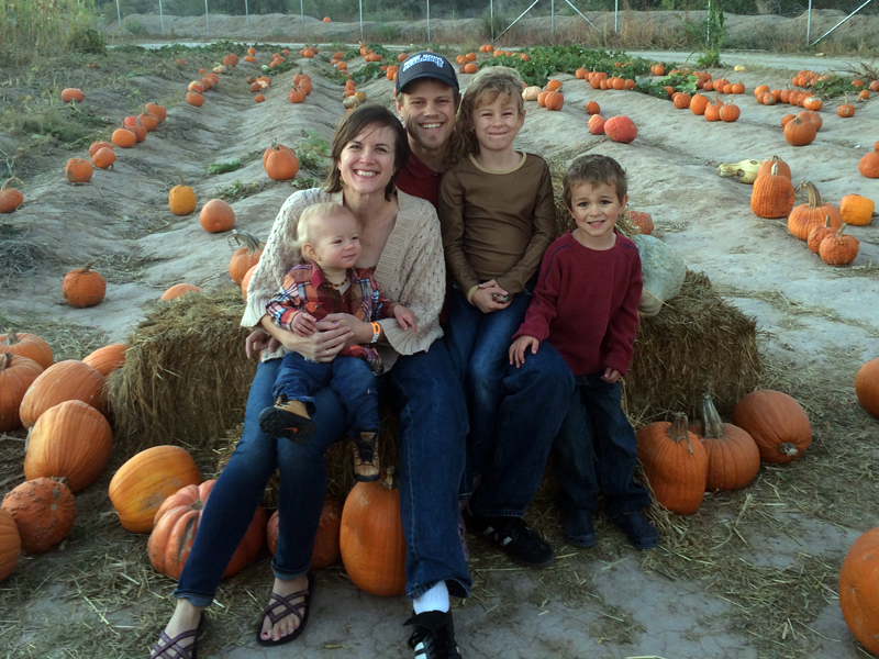Joel, Amy, Jordan, Elayne and Titus sitting on a hay bale surrounded by pumpkins!