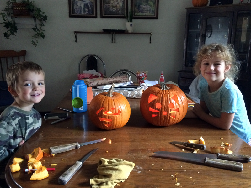 Titus and Elayne show off their pumpkin carvings: a Superman shield and a kitty-cat face