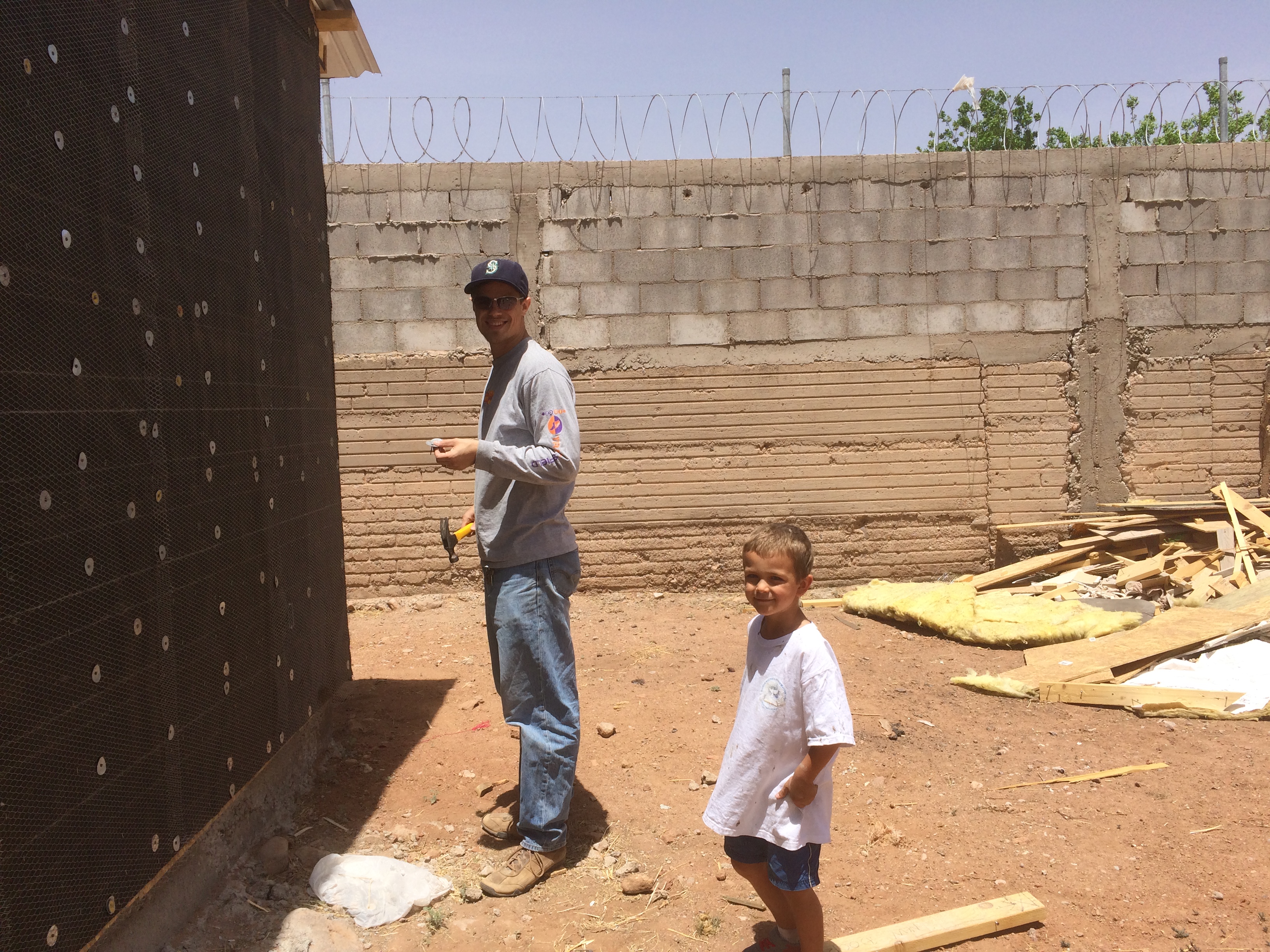 Jordan and Titus, standing in front of an unfinished outer wall for the new Jireh church building