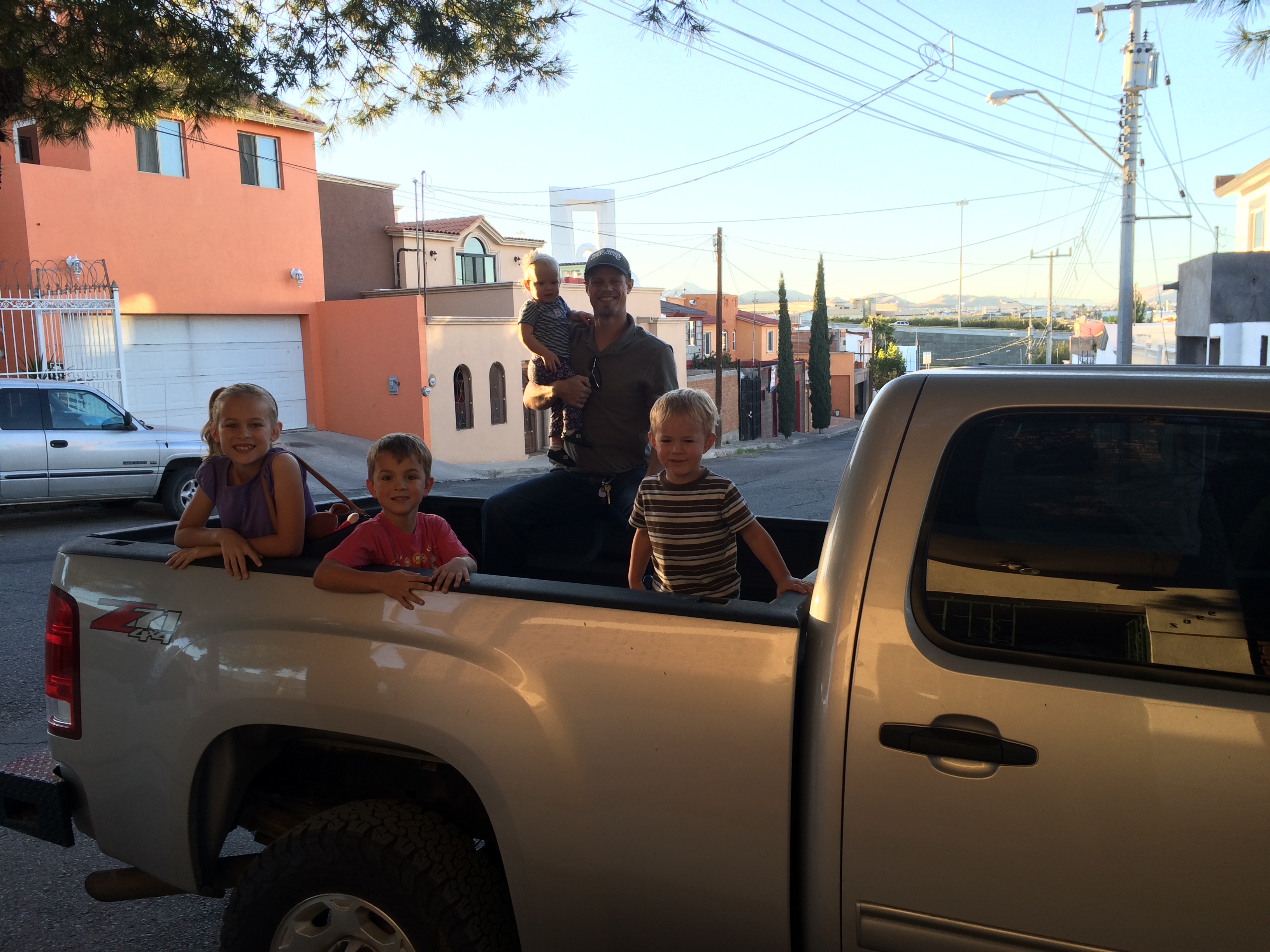 Elayne, Titus, Jordan (holding Lily), and Joel in the bed of our new truck - with beautiful Chihuahua finally in the background!