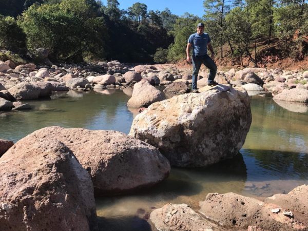 A friend of a friend, standing on top of a gigantic rock in the middle of some shallow water. It used to be in the middle of our road...