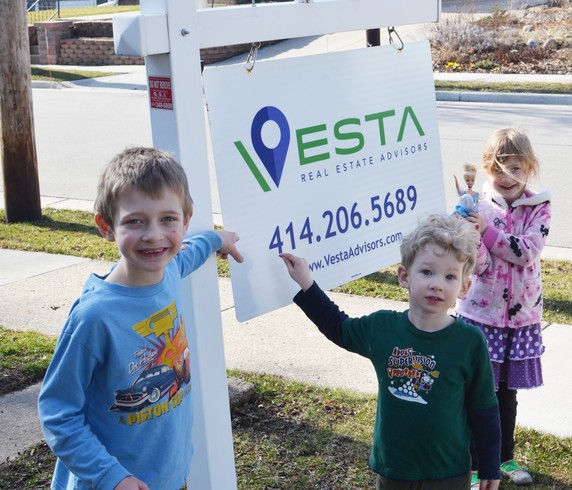 The real estate sign & the kids pointing at it.